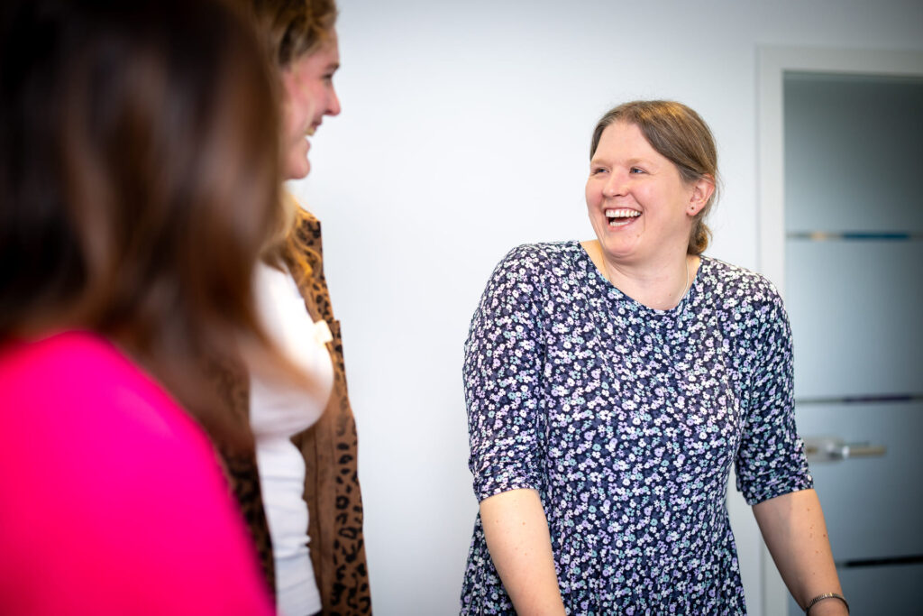 Birgit Sparenberg im Coaching. Lacht mit zwei Teilnehmenden.